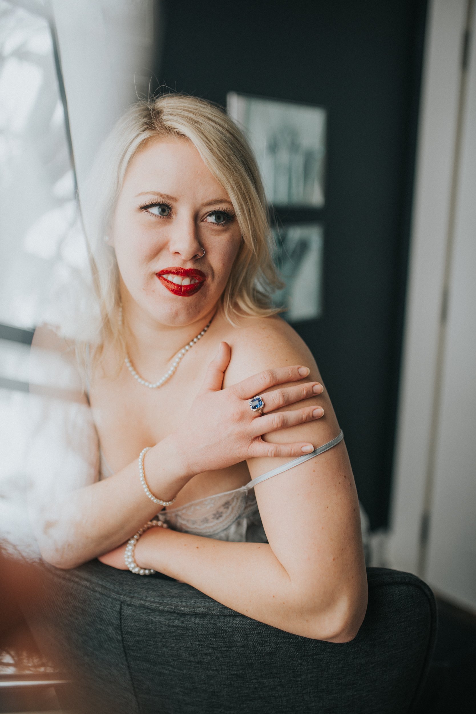 woman in red lipstick and vintage lingerie wearing a vintage ring durring her boudoir photography session in st paul