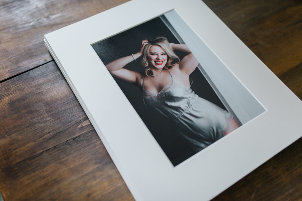 Mounted and matted boudoir portrait of smiling woman with red lipstick and blond hair. Photograph by St Paul Boudoir Photographer Madelin Zaycheck 